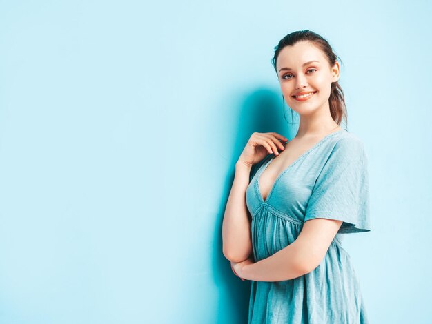 Portret van jonge mooie lachende vrouw in trendy zomer blauwe jurk Sexy zorgeloze vrouw poseren in de buurt van blauwe muur in studio Positief model plezier en gek vrolijk en gelukkig