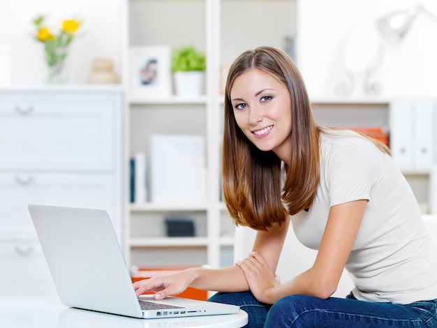 Portret van jonge mooie lachende vrouw wordt afgedrukt op de laptop