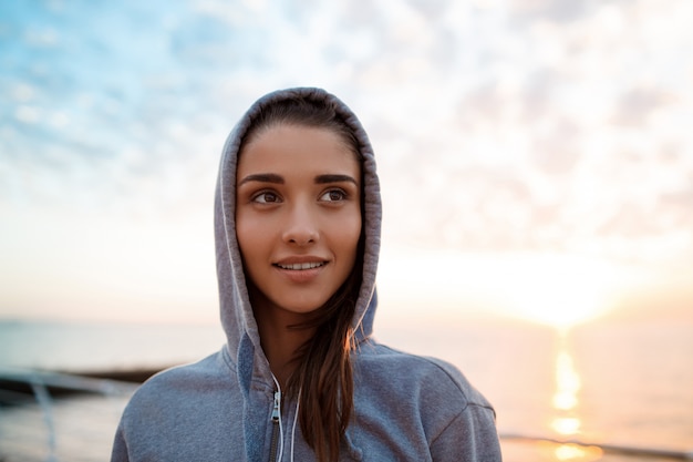 Portret van jonge mooie sportieve meisje bij zonsopgang boven zee.