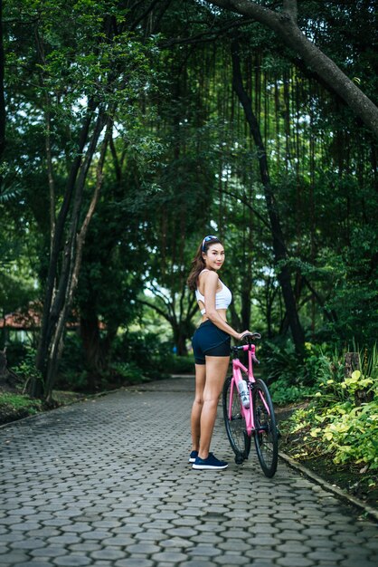 Portret van jonge mooie vrouw met roze fiets in het park. Actractive gezonde vrouw.
