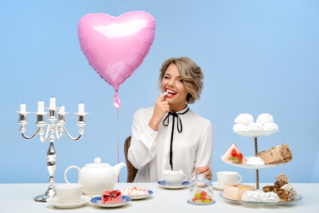 Portret van jonge mooie vrouw met snoep over blauwe muur