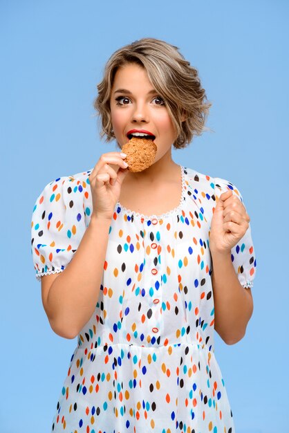 Portret van jonge mooie vrouw met snoep over blauwe muur