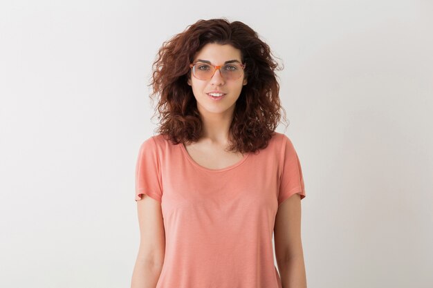 Portret van jonge natuurlijke lachende hipster mooie vrouw met krullend kapsel in roze shirt poseren dragen van een bril geïsoleerd op witte studio achtergrond