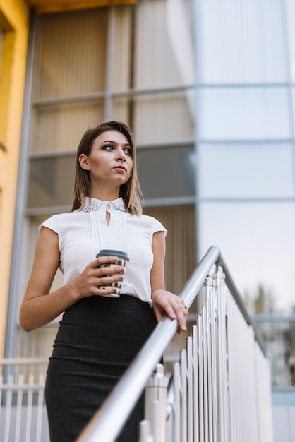 Portret van jonge onderneemster die meeneemkoffiekop houden in openlucht