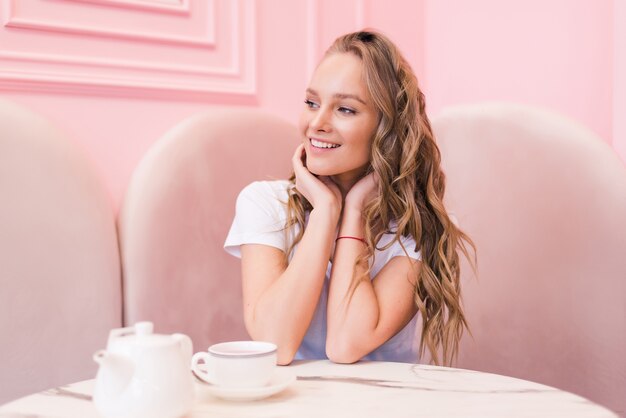 Portret van jonge prachtige vrouwelijke het drinken van thee in modern café tijdens haar werkpauze