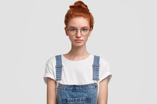 Portret van jonge roodharige vrouw, gekleed in denim overall