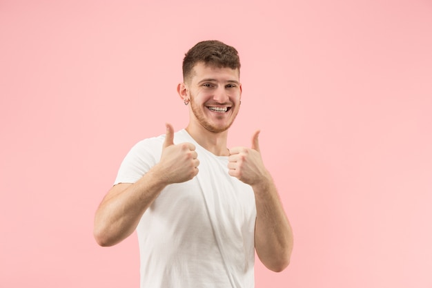 Portret van jonge trendy man op roze achtergrond. Emotionele uitdrukking.