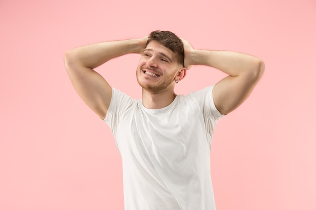 Portret van jonge trendy man op roze achtergrond. Emotionele uitdrukking.