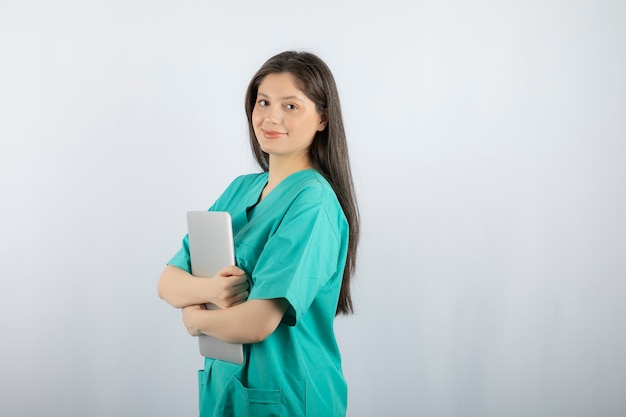 Portret van jonge verpleegster met laptop op wit.