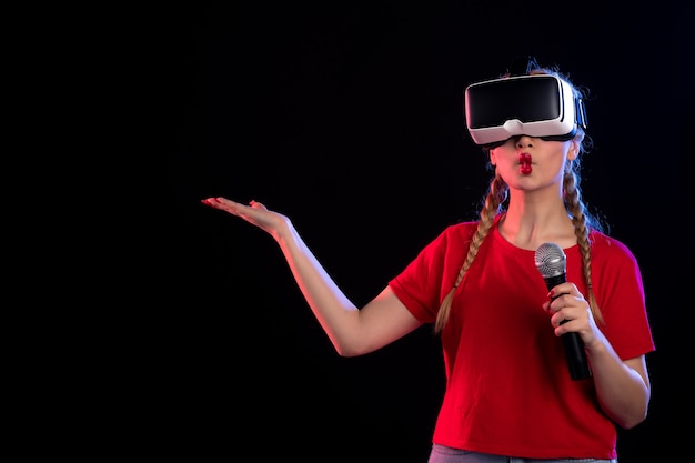 Portret van jonge vrouw die vr speelt en zingt met mic donkere visuele muziekgames