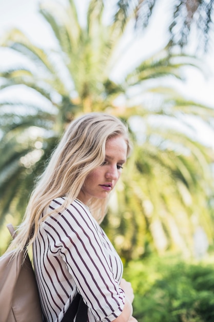 Portret van jonge vrouw die zich vooraan boom bevindt