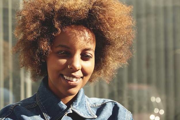 Portret van jonge vrouw met krullend haar die denimoverhemd dragen