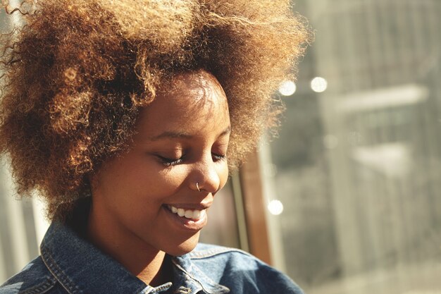 Portret van jonge vrouw met krullend haar die denimoverhemd dragen