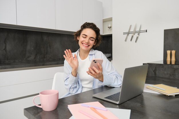 Portret van jonge vrouw videochats met vriend op smartphone golven hand op mobiele telefooncamera