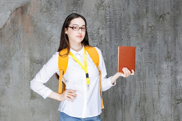 Portret van jonge vrouwelijke student in glazen die zich met boek bevinden. hoge kwaliteit foto