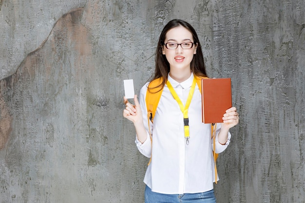 Portret van jonge vrouwelijke student in glazen met visitekaartje en boek. hoge kwaliteit foto