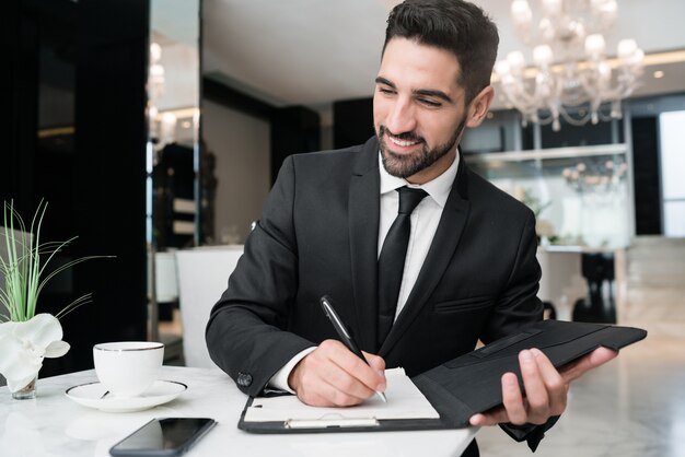 Portret van jonge zakenman die bij de hotellobby werkt. Zakelijke reizen concept.