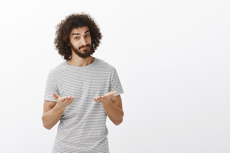 Gratis Foto portret van kalme en zelfverzekerde aantrekkelijke werkgever in gestreept overhemd, gelegenheid geven om mening te uiten, wijzend met handpalmen