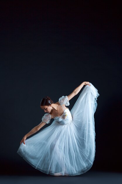Portret van klassieke ballerina in witte jurk op zwart