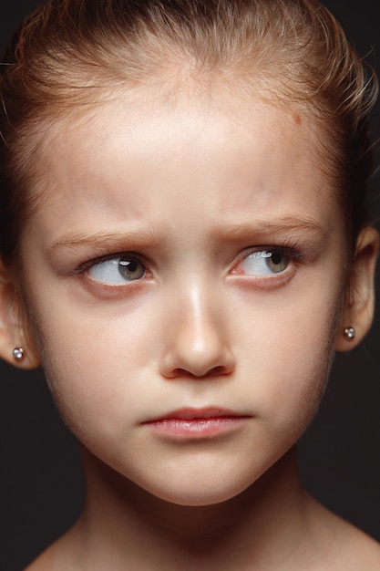 Portret van klein en emotioneel Kaukasisch meisje close-up. Zeer gedetailleerde fotoshoot van een vrouwelijk model met een verzorgde huid en een heldere gezichtsuitdrukking. Concept van menselijke emoties. Verdrietig, van streek.