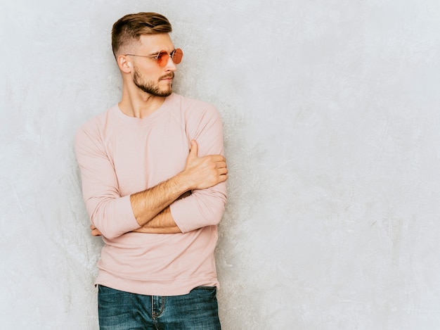 Portret van knap het glimlachen jonge mensenmodel die toevallige de zomer roze kleren dragen. Mode stijlvolle man poseren in ronde zonnebril