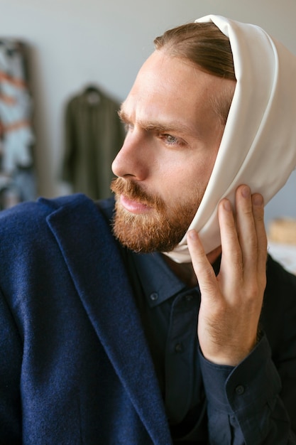 Gratis foto portret van knappe bebaarde man met oorverband in een kunststudio