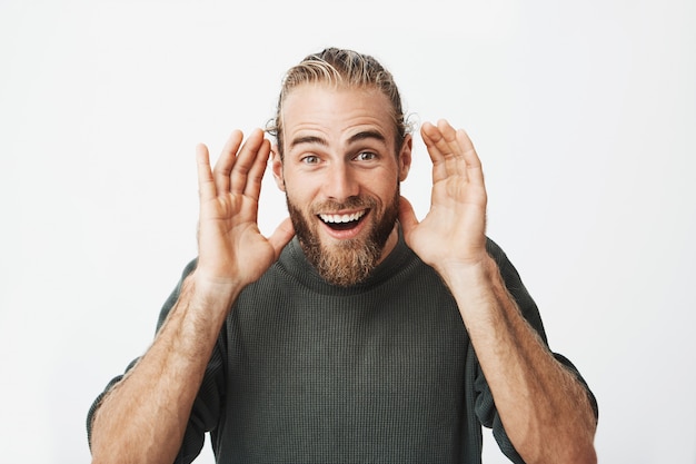 portret van knappe bebaarde man met stijlvolle kapsel gekke gezichten maken.