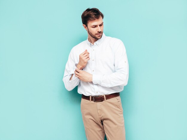 Portret van knappe lachende model Sexy stijlvolle man gekleed in shirt en broek Fashion hipster man poseren in de buurt van blauwe muur in studio geïsoleerd