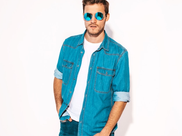 Portret van knappe lachende stijlvolle jonge man model dragen jeans kleding en zonnebril. Mode man