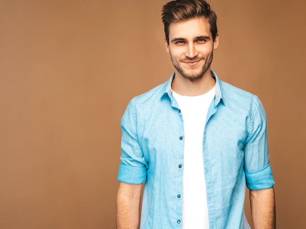 Portret van knappe lachende stijlvolle jonge man model gekleed in blauwe shirt kleding. mode man die zich voordeed