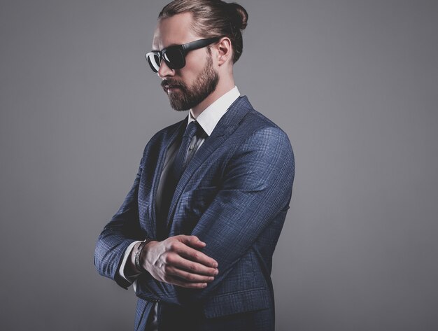 portret van knappe mode zakenman model gekleed in elegant blauw pak met zonnebril