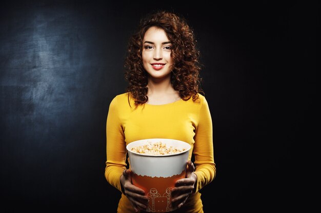 Portret van krullende de popcornemmer die van de vrouwenholding recht kijken