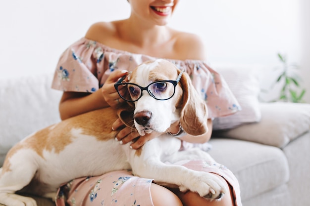 Portret van lachend meisje in roze jurk met droevige beagle hond in glazen op voorgrond