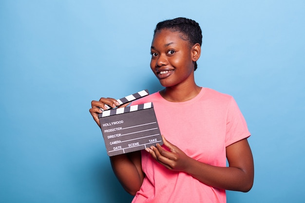 Portret van lachende Afro-Amerikaanse jonge vrouw met filmproductie schoolbord