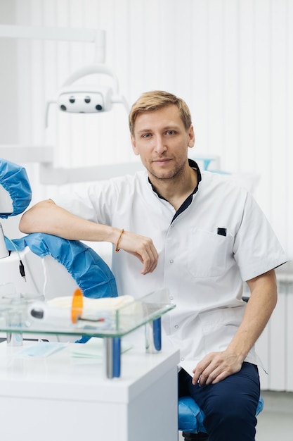 Portret van lachende blanke man tandarts poseren bij moderne tandartspraktijk.