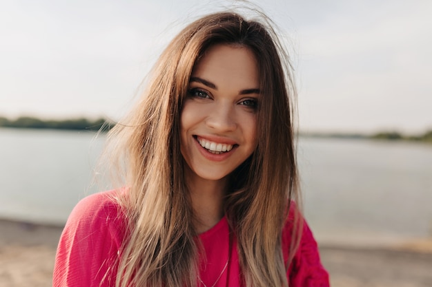 Portret van lachende charmante dame met donker haar gekleed roze shirt glimlachen close-up