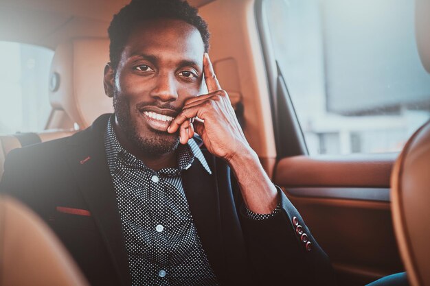 Portret van lachende elegante afro etnicity zakenman in de auto als passagier.