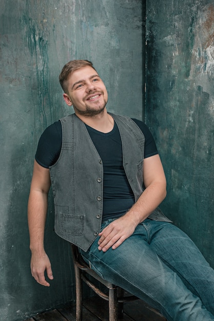 Gratis foto portret van lachende gelukkig man zittend op de stoel