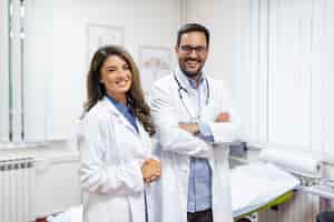 Gratis foto portret van lachende jonge artsen die samen staan portret van medisch personeel in het moderne ziekenhuis dat naar de camera glimlacht