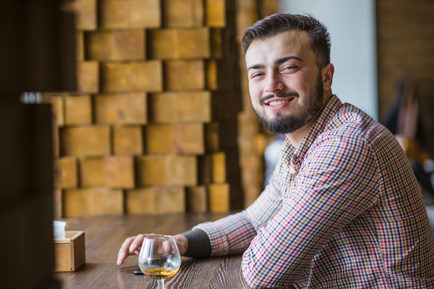 Gratis foto portret van lachende jonge man zit op restaurant