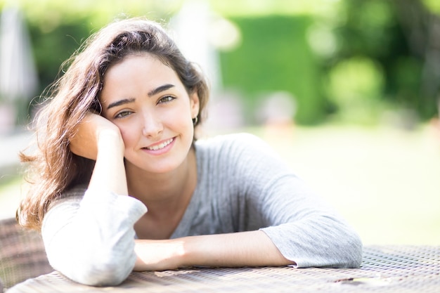 Portret van lachende jonge vrouw aan tafel zitten