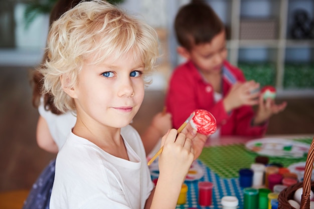 Portret van lachende jongen die paaseieren schildert