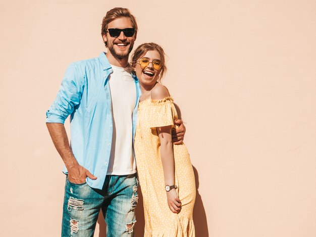 Portret van lachende mooi meisje en haar knappe vriendje. Vrouw in casual zomerjurk en man in spijkerbroek. Gelukkige vrolijke familie. Vrouw plezier in de straat in de buurt van muur