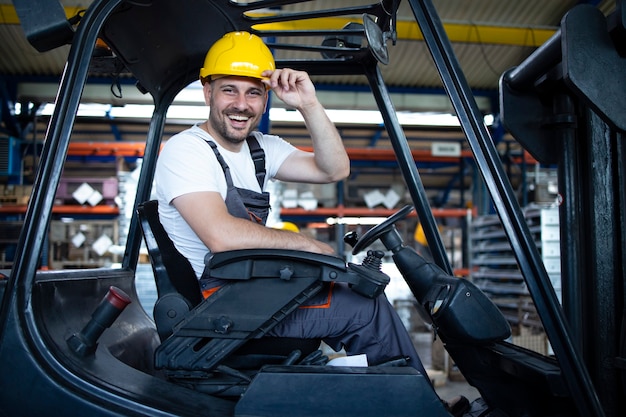 Portret van lachende professionele heftruckchauffeur in het magazijn van de fabriek