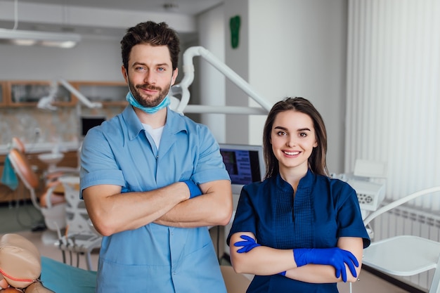 Portret van lachende tandarts permanent met armen gekruist met haar collega.