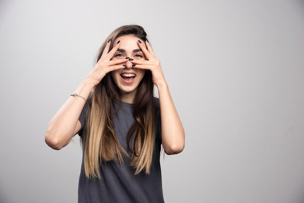 Portret van lachende vrouw aan haar gezicht poseren over grijze achtergrond te raken.