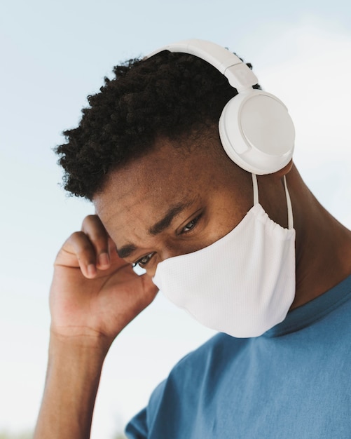 Portret van man buitenshuis met koptelefoon en gezichtsmasker