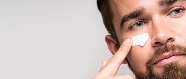 Portret van man met behulp van gezichtscrème met kopie ruimte