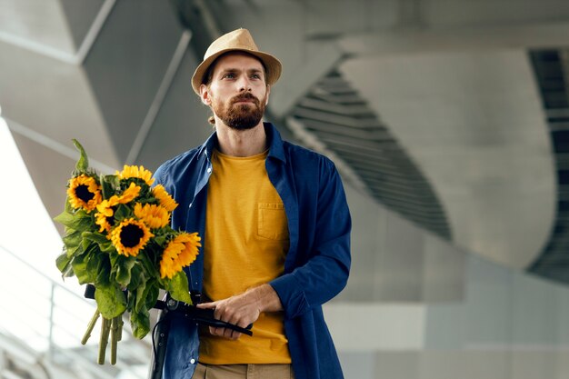 Portret van man met zonnebloemen op elektrische scooter buiten