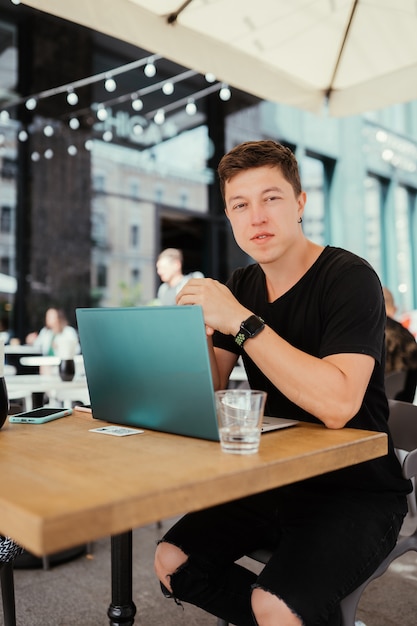 Portret van man zittend aan een tafel die werkt op een laptopcomputer.